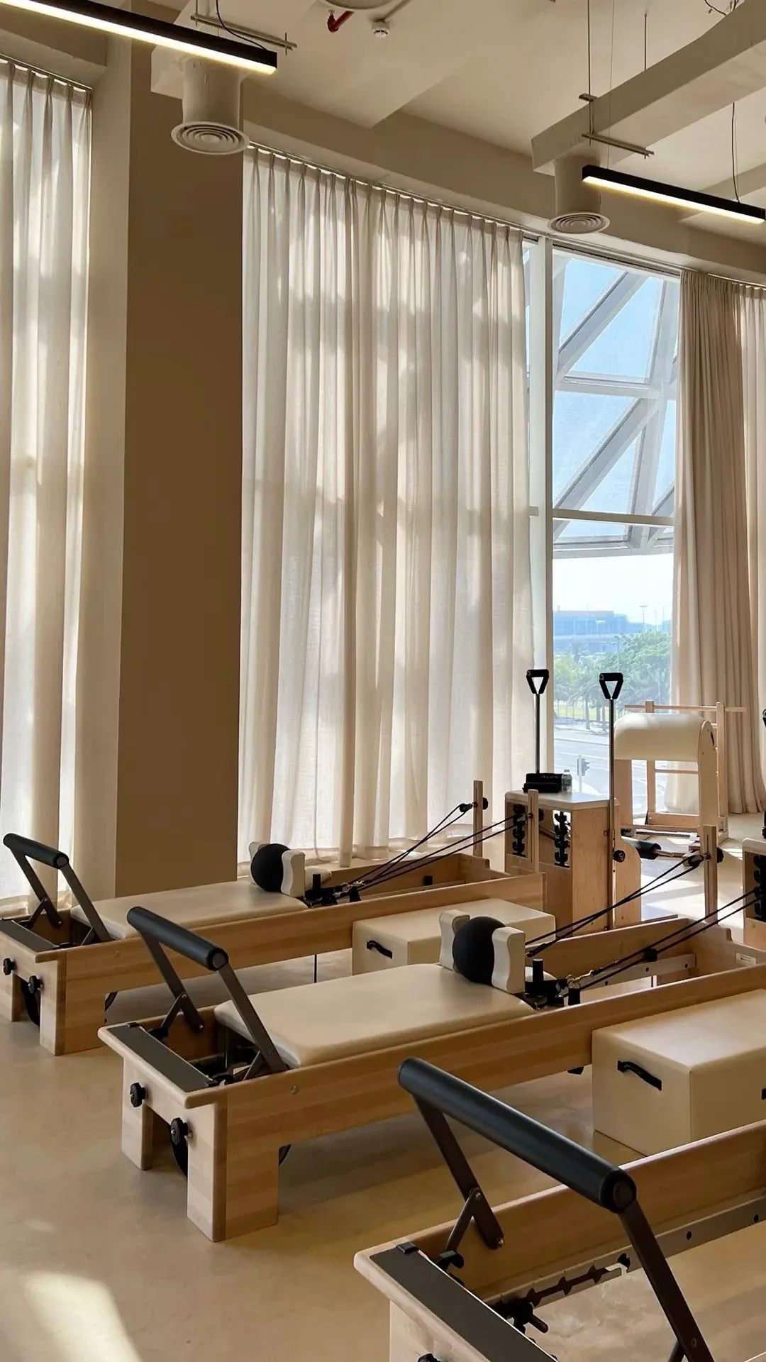 Pilates reformers in a sun-soaked studio with sheer curtains