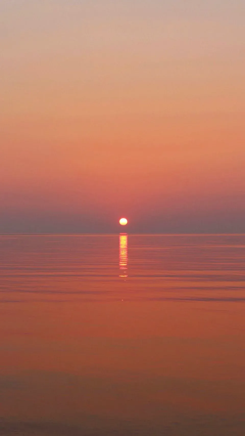 A perfectly flat sunset over still water, sun just touching the horizon