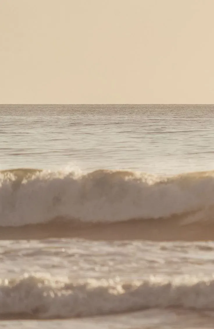 Calm golden-hour waves rolling onto a warm sand beach